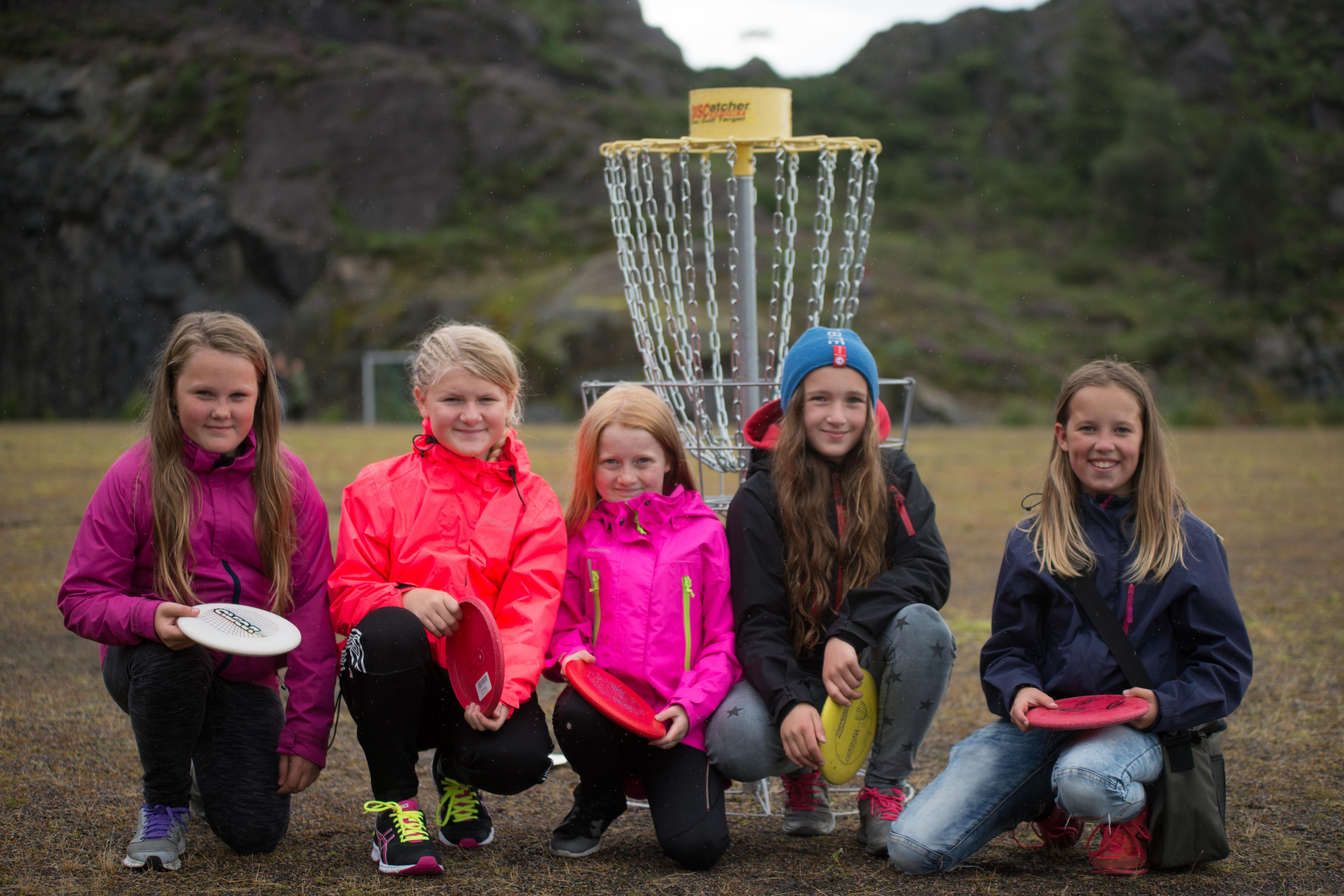 Fem jenter på huk med hver sin frisbee